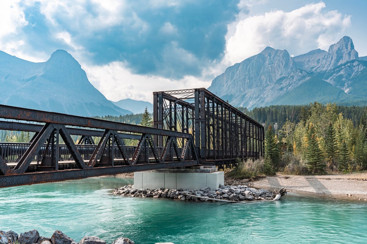 Historic iron bridge set against mountain peaks at golden hour
